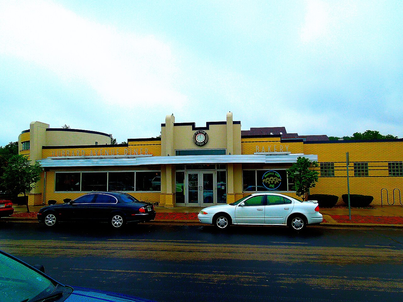 The exterior of a classic American diner, a low streamlined building with neon signs