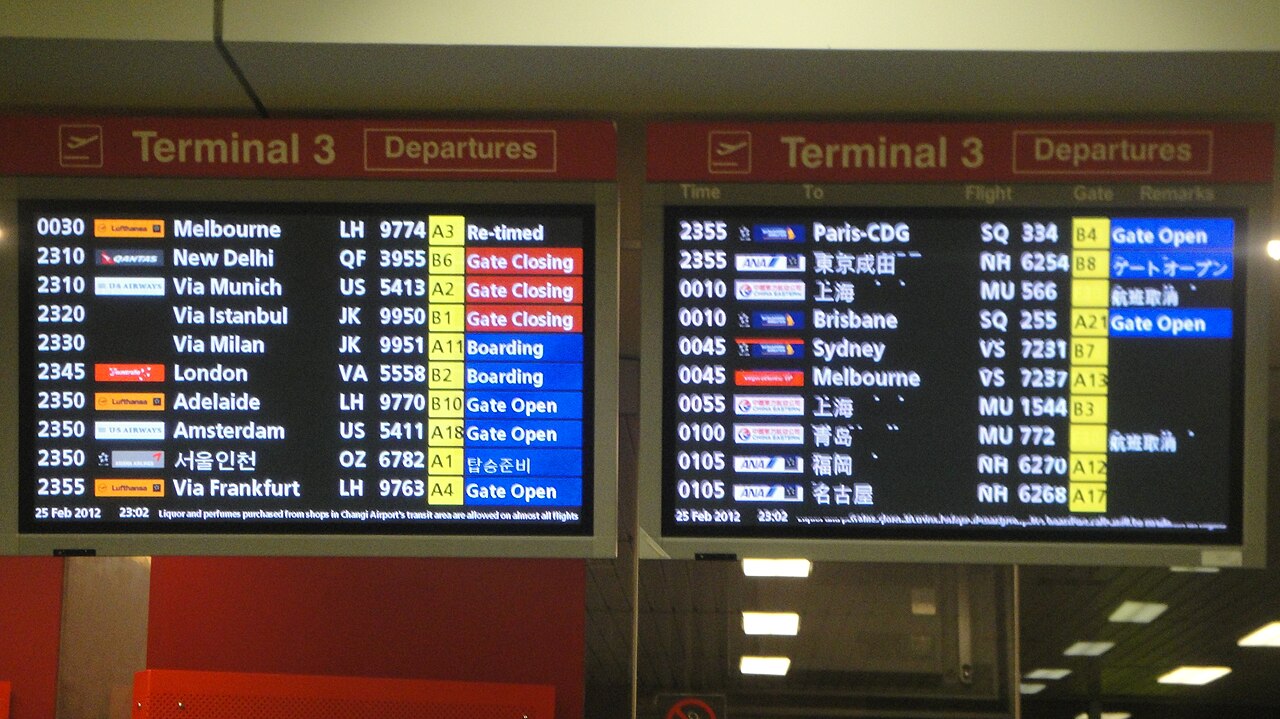 An airport departures board listing flights, times, destinations, gate numbers and status such as Boarding and Gate Open