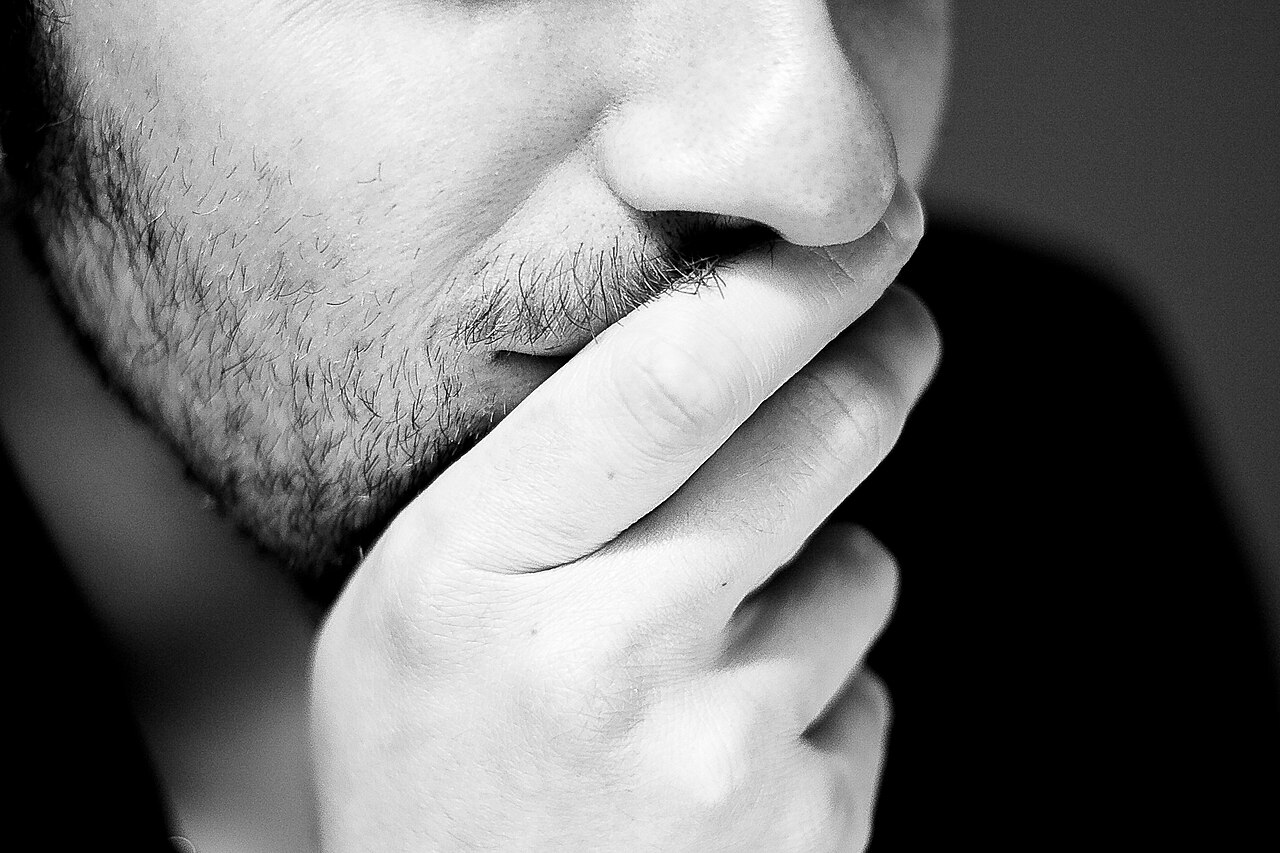 A close-up of a person resting their chin on their hand, deep in thought