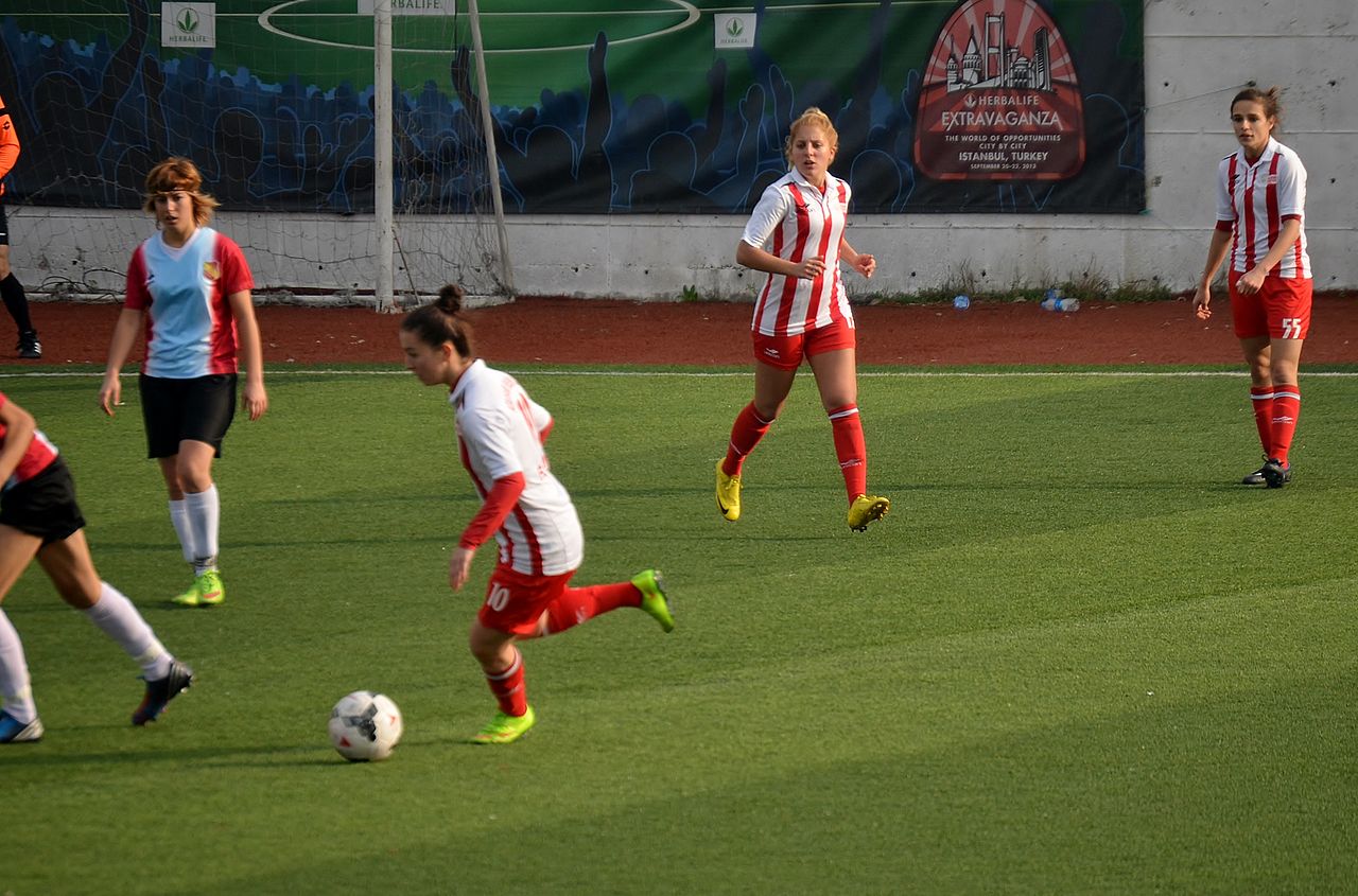 A soccer player running forward with the ball at her feet during a match