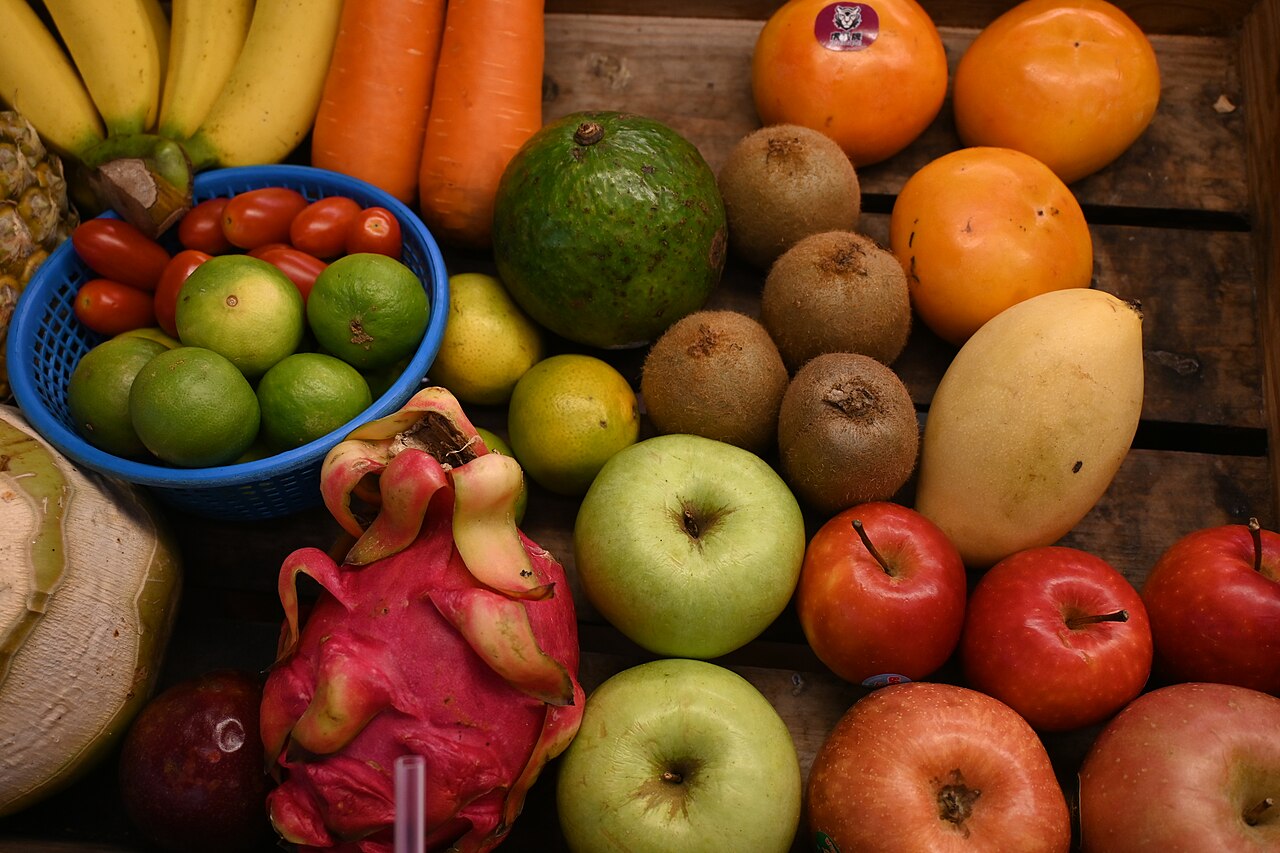 A colorful assortment of fresh fruits and vegetables on a wooden crate