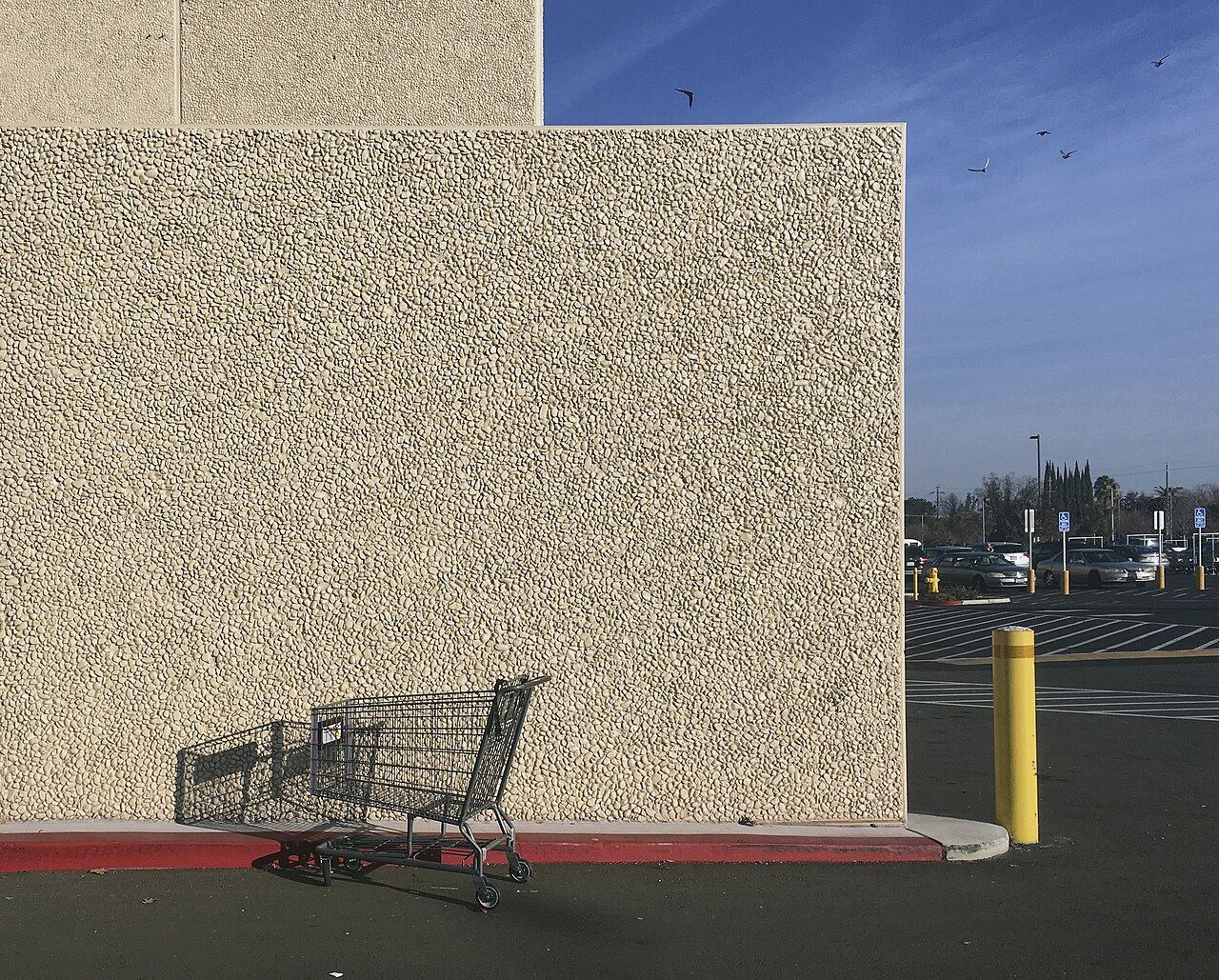 A metal shopping cart in the parking lot of an American store