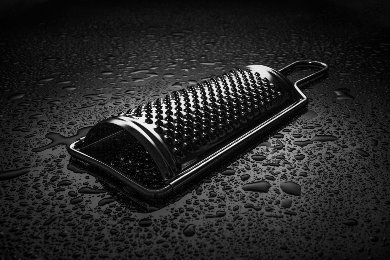 A handheld metal grater, used to grate food such as cheese into thin shreds