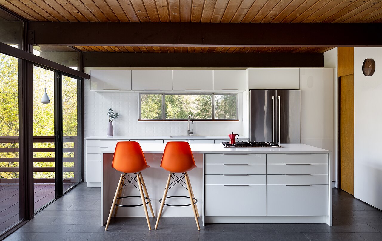 A modern kitchen showing white cabinets, a countertop, a stovetop, a sink and a faucet