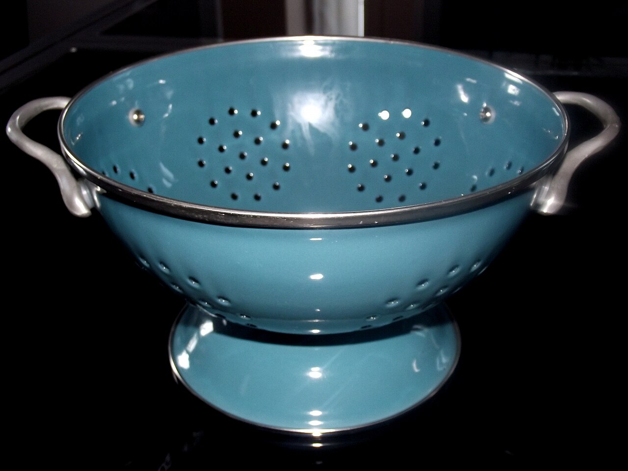 A blue colander, a bowl full of holes used to drain water away from food