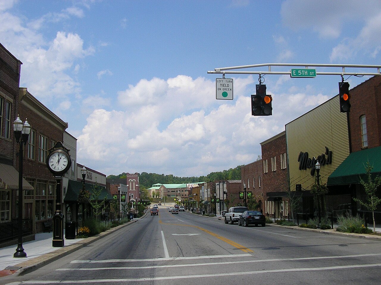A small-town American Main Street with a marked crosswalk, a traffic light, street signs and sidewalks on both sides