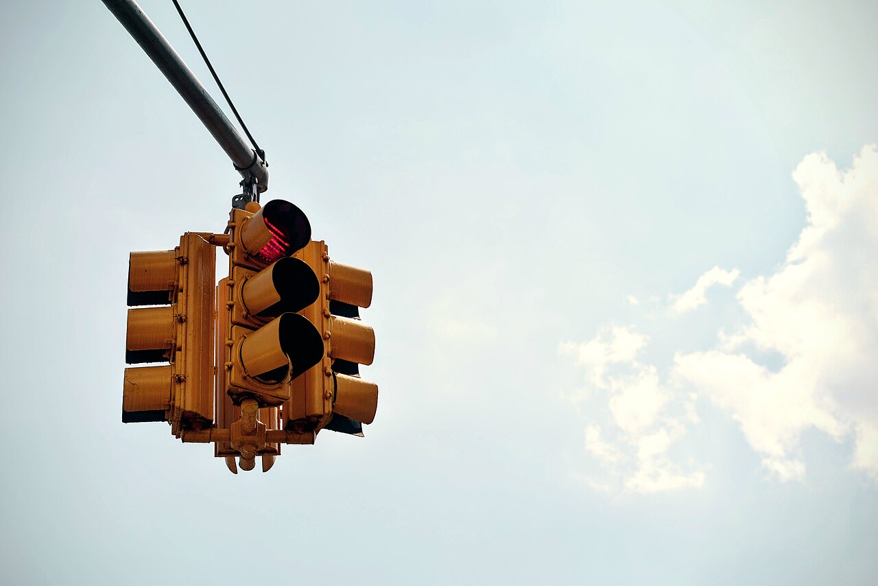 A yellow American traffic light showing red, hanging over an intersection