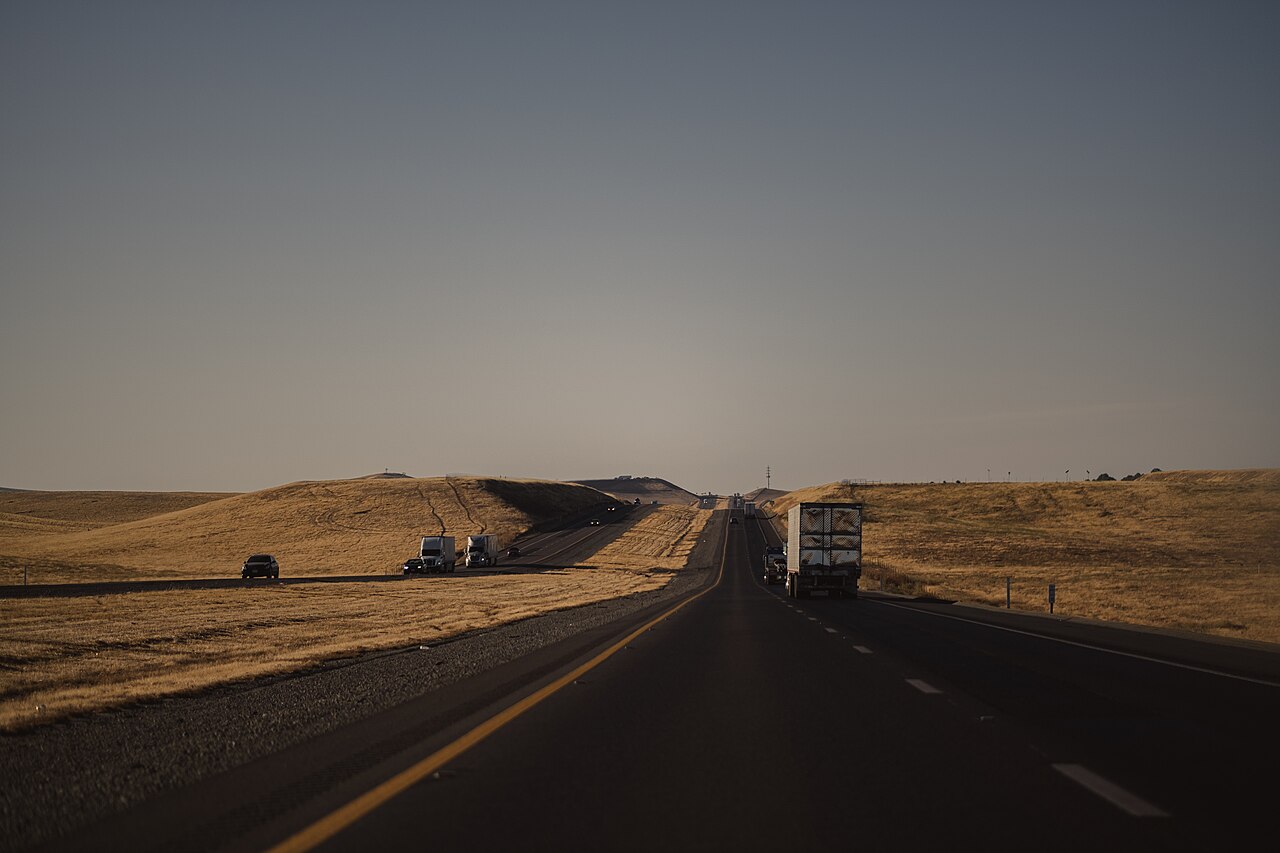 An open American highway with two lanes each way, a painted center line and a paved shoulder