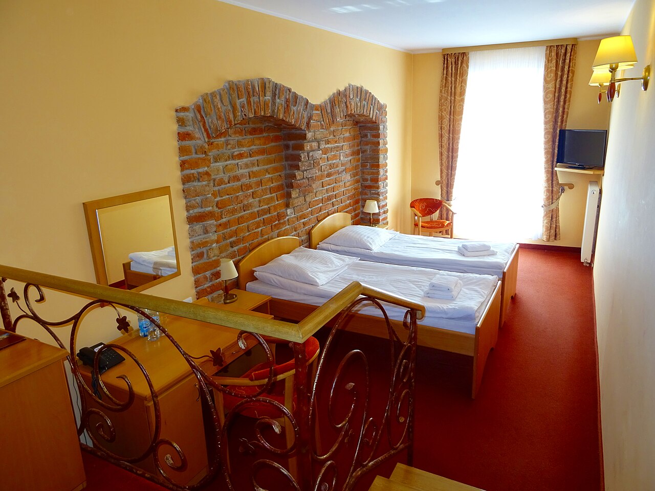 A hotel room with two beds, a window, and a television