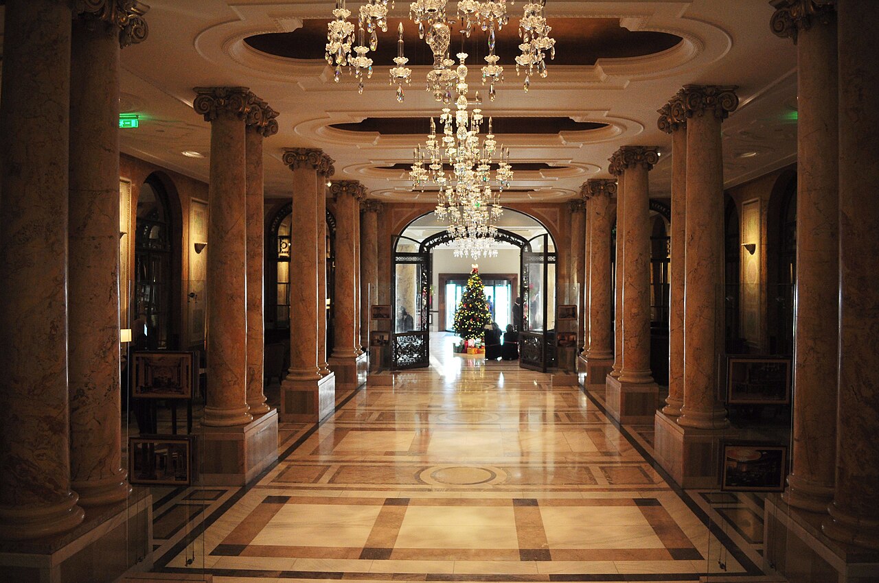 The grand lobby of a hotel with chandeliers and marble columns